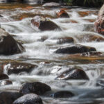 5.0 - The large rocks to each side draw my eye to the back of theframe—a good compositional technique. You may have severalexposure times of this same composition. Some may prefer the moreveiled water whereas this image has just a touch of a longer exposure;a personal preference. I see several highlights bordering on being over-blown; maybe a less direct angle of the sun would help, that is,later/earlier in the day. Even with the large rocks (slightly out of focus)framing the image, my eye still wanders seeking a point of interest;cropping the lower one-third of the image, or at least the blurrywater/rocks on the lower right, may benefit. Thank you for the straighthorizon!