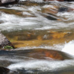 5.8 - The photographer has chosen a good shutter speed to capture the rushing water and still maintain the colors on the rocks and riverbed. However, way over exposed splashes on the right side are very distracting.